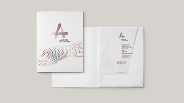 Weiße Mappe offen und geschlossen mit Logo Akademie für Ausbilder