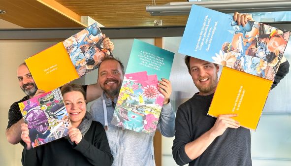 Sascha Grabherr, Petra Lorenz, Mario Lorenz und Alex Welzenbach freuen sich und halten den Euram Bank Geschäftsbericht aus dem Jahr 2022 in die Luft.